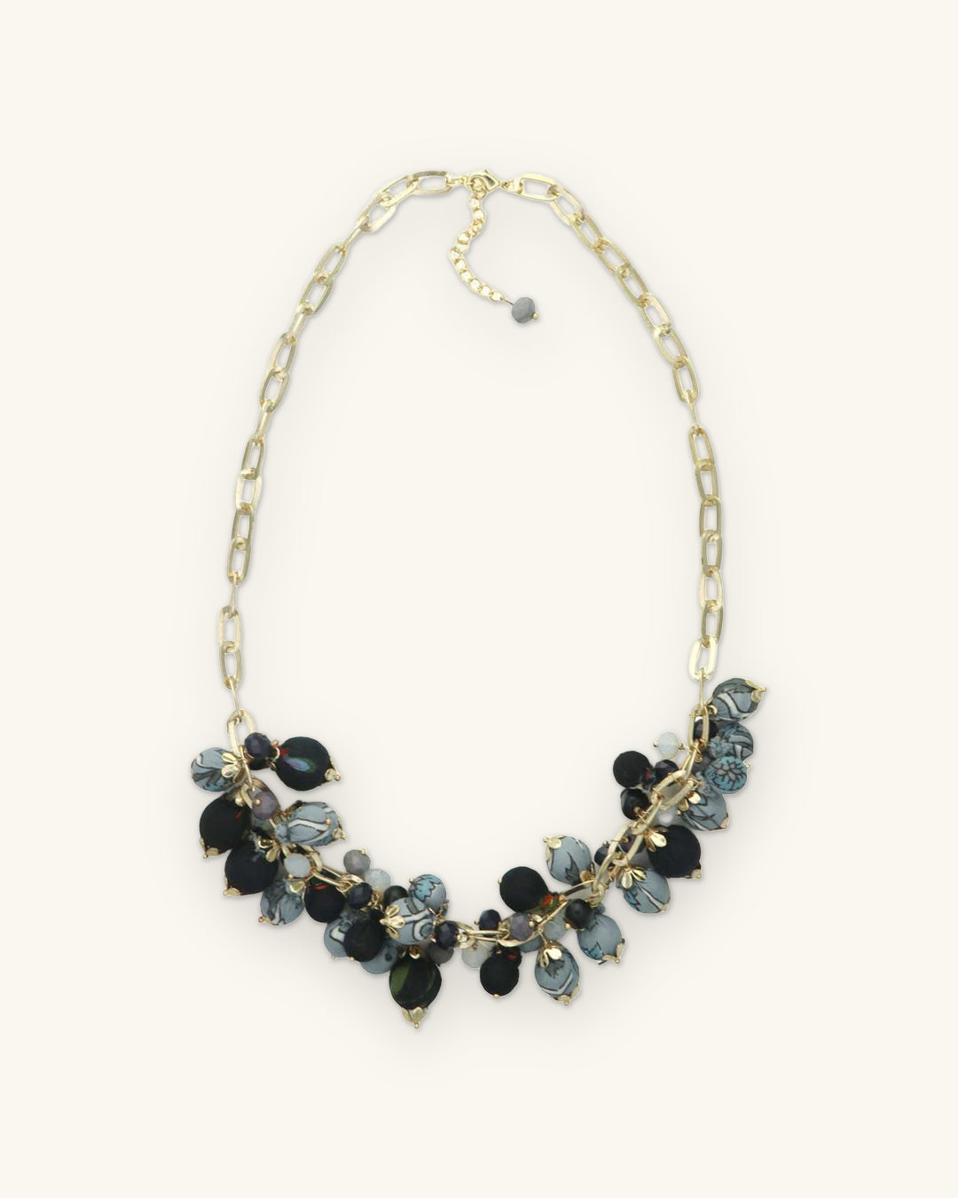 Full length of the clustered fabric bead necklace on a gold-plated brass paperclip chain, shown on a sand background