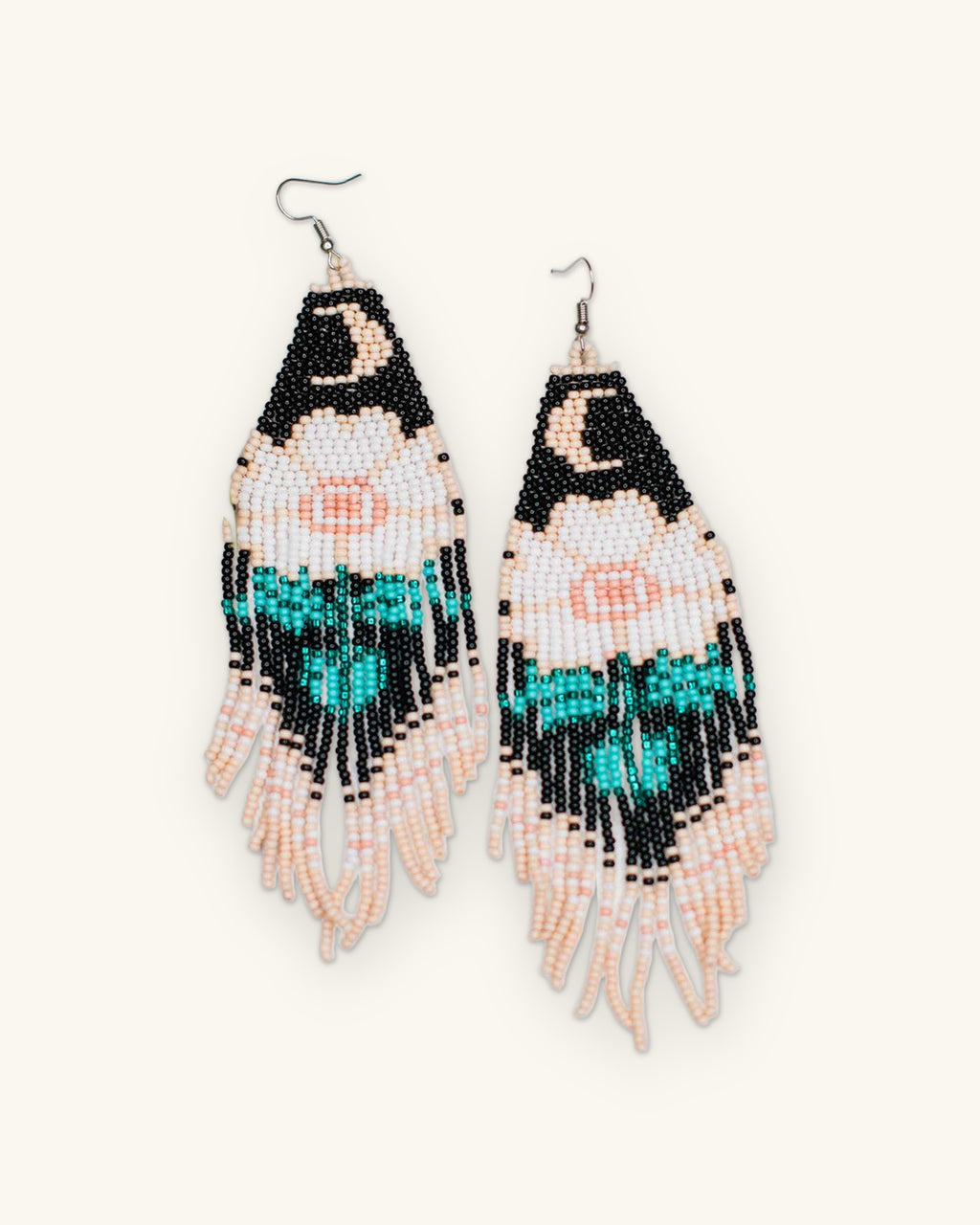 Black, turquoise and blush glass seed bead fringe earrings with crescent moon and flower motif, handmade in Guatemala, shown on a sand background