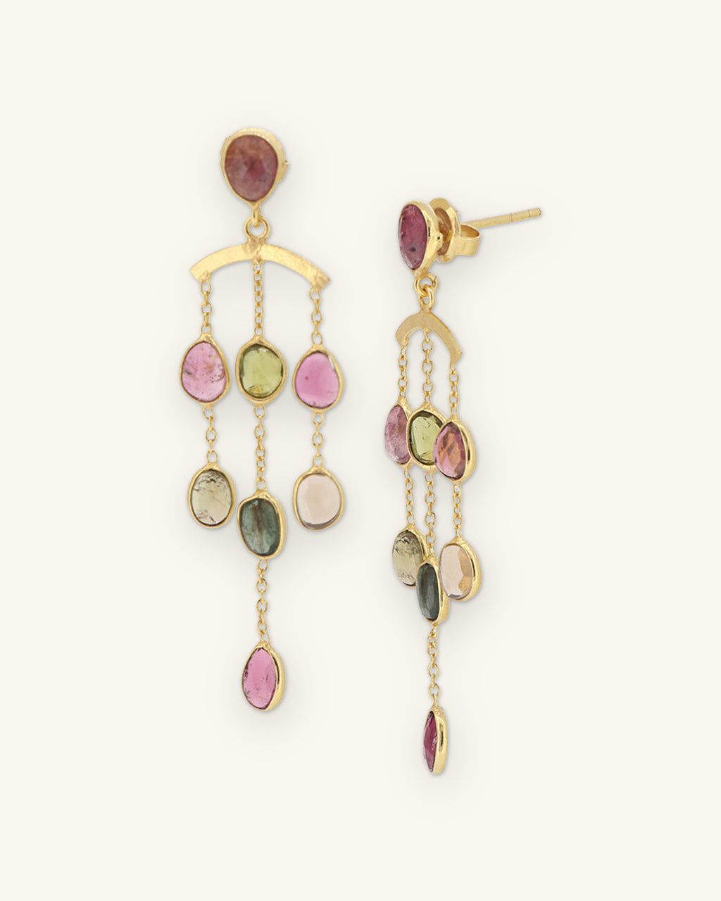 Gold-plated brass chandelier earrings with bezel-set pink, green and peach tourmaline drops, made in India, shown on a sand background