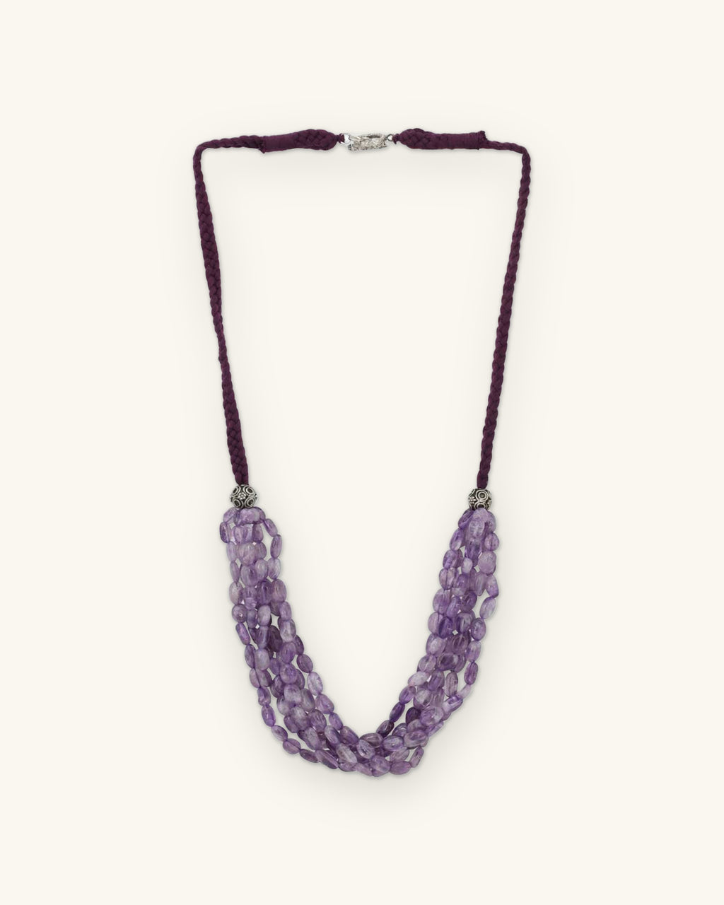 Multi-strand amethyst nugget necklace on a plum braided cotton cord with silver-tone caps, made in India, shown on a sand background
