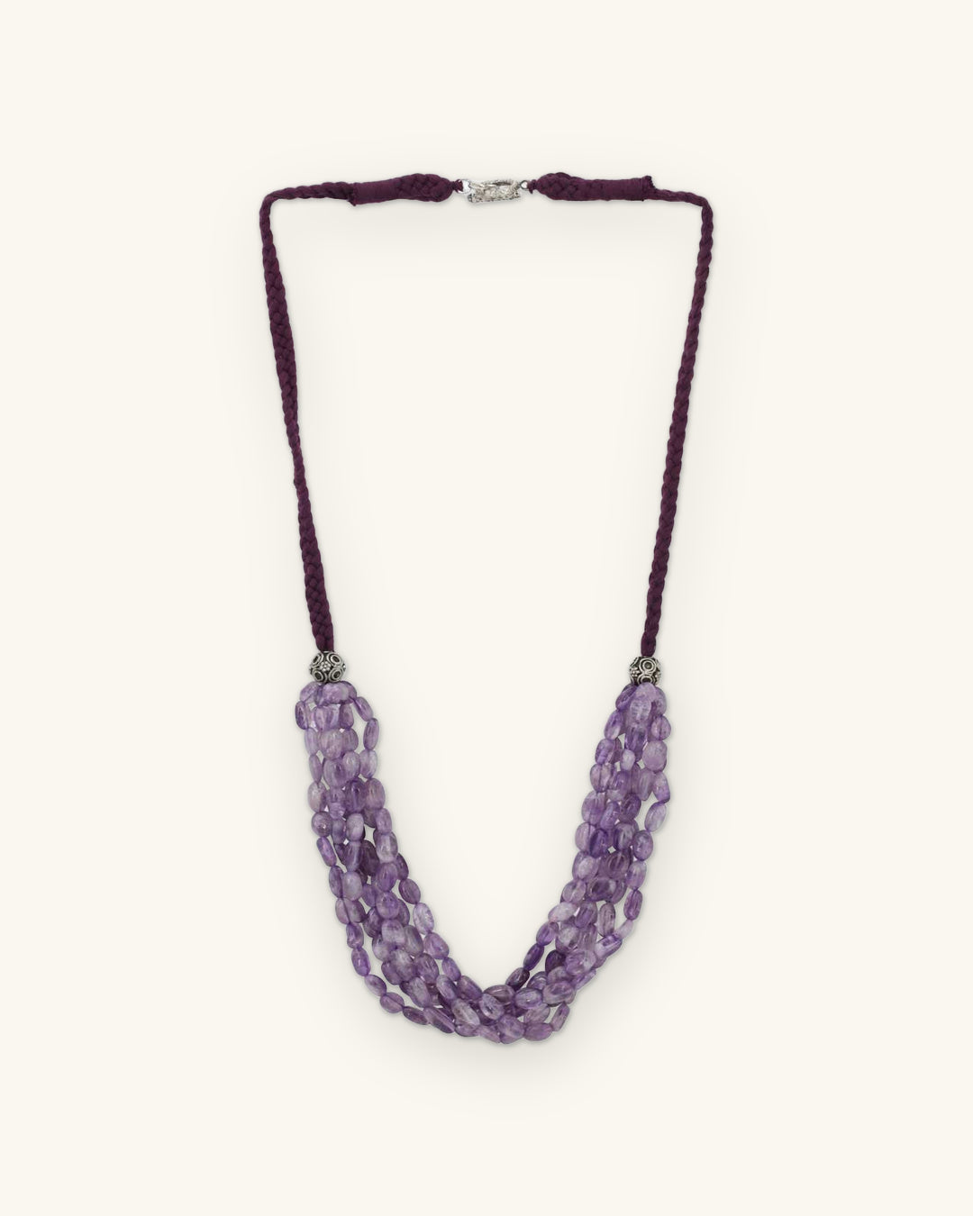 Multi-strand amethyst nugget necklace on a plum braided cotton cord with silver-tone caps, made in India, shown on a sand background