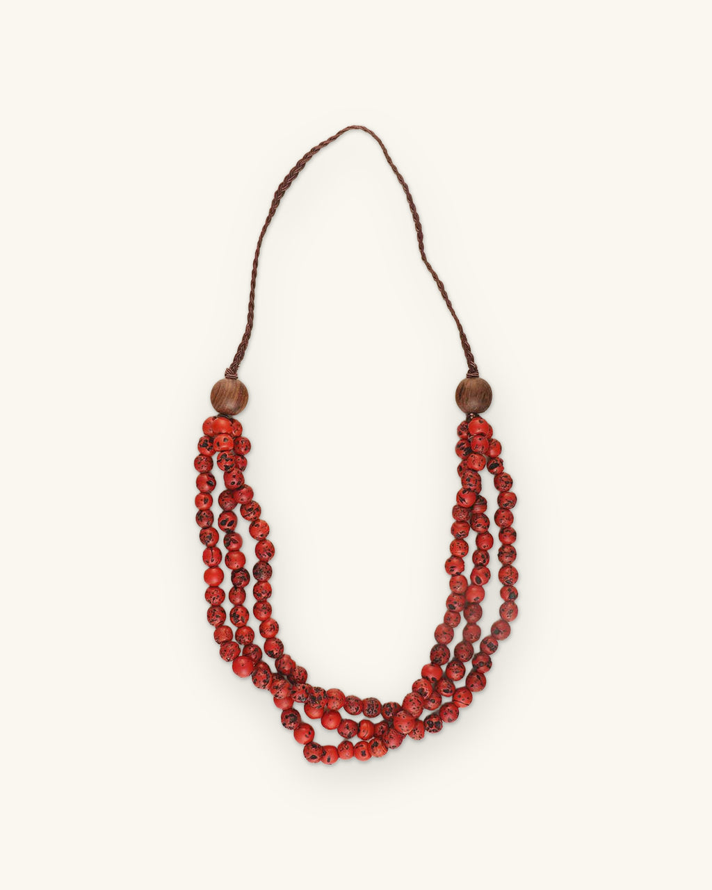 Three-strand speckled glass bead necklace in Red with wooden accent beads and brown braided cord, shown on a sand background