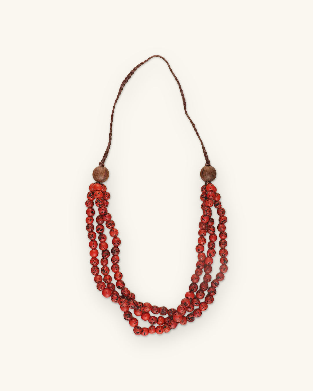 Three-strand speckled glass bead necklace in Red with wooden accent beads and brown braided cord, shown on a sand background