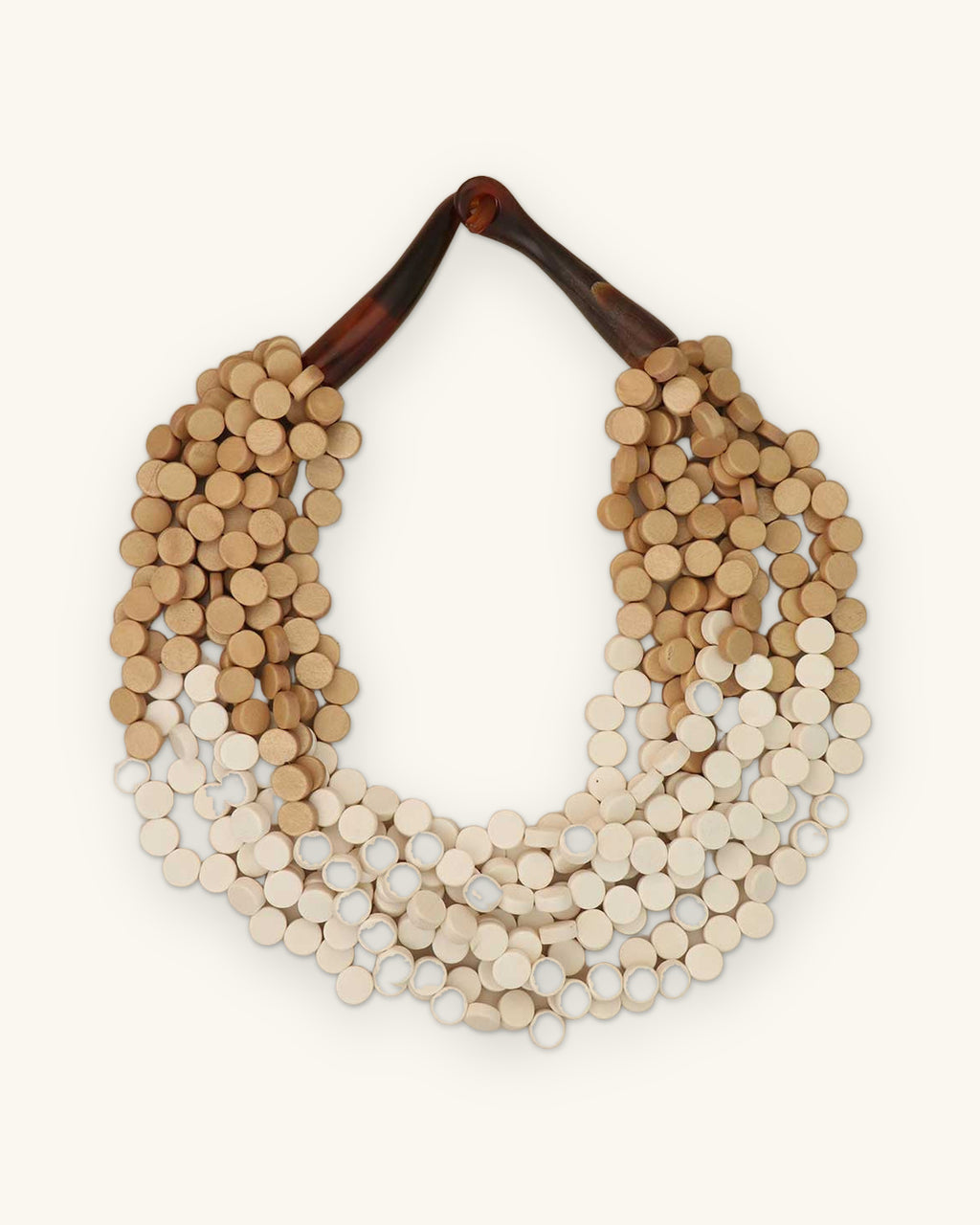 Multi-strand wood disc bib necklace in cream-to-beige ombré with carved horn closure, hand-cut in the Philippines, shown on a sand background