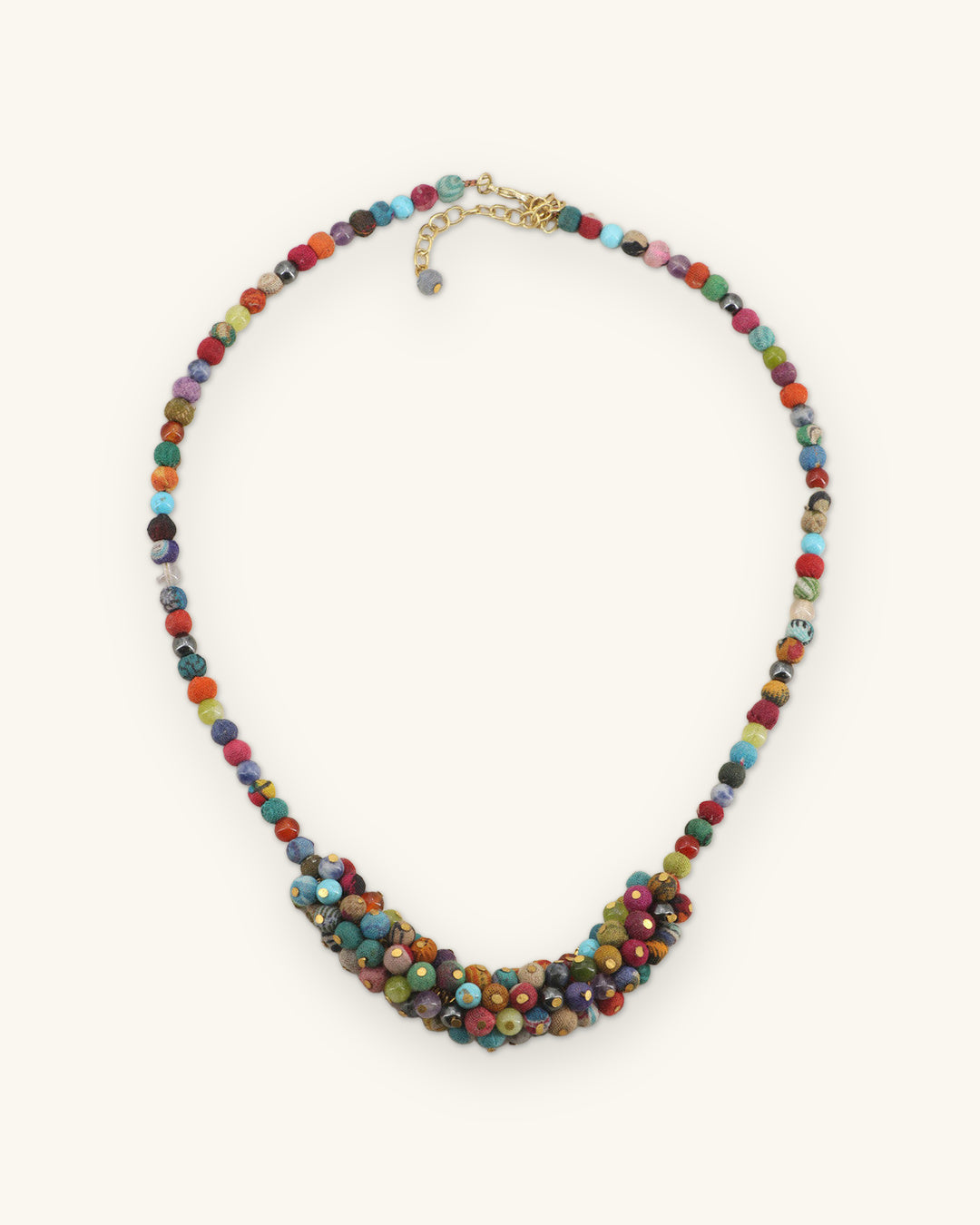 Full view of the multicolor bead strand necklace with clustered center and gold-tone lobster clasp, shown on a sand background
