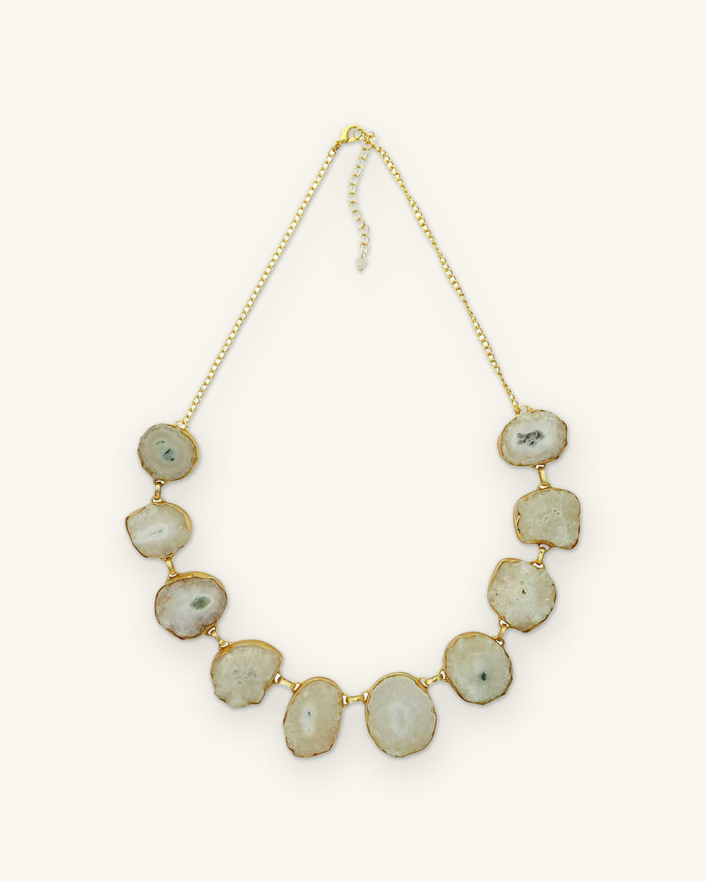 Full view of the white agate slice necklace with gold-plated brass chain and extender, shown on a sand background