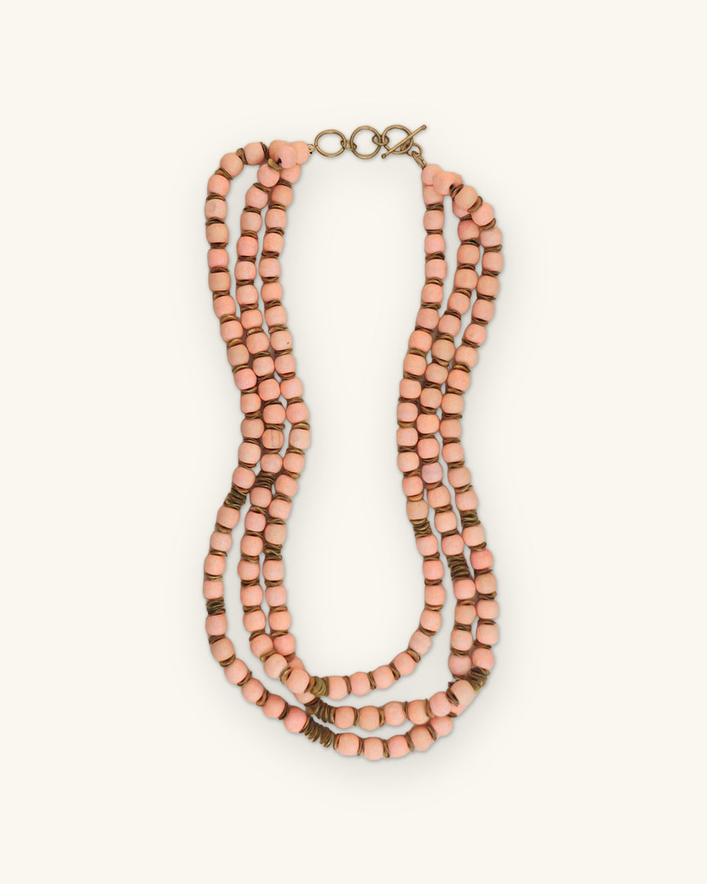 Three-strand peach wood bead necklace with wavy brass spacers and ring closure, hand-turned and hand-strung in India, shown on a sand background