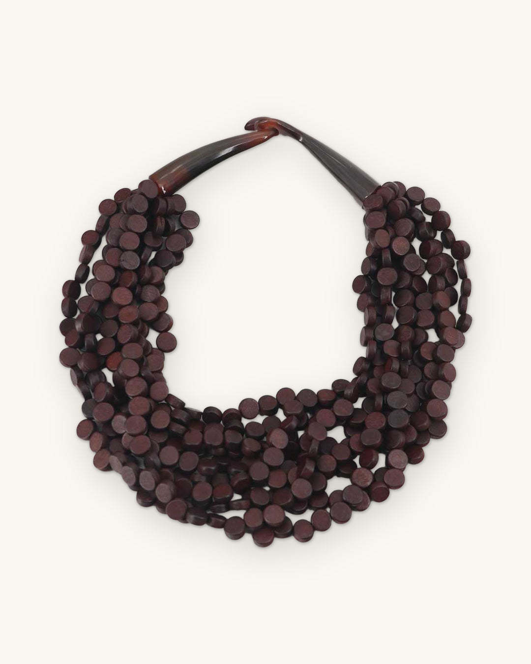 Deep brown wood disc multi-strand necklace with a curved horn closure, full view, shown on a sand background