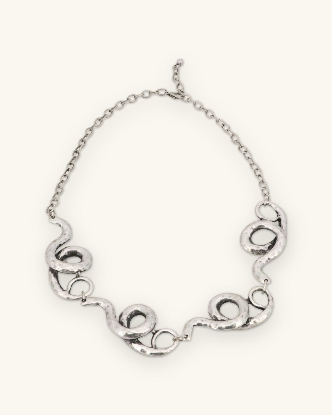 Hammered silver-tone spiral link necklace with lobster clasp and extender chain, full view, shown on a sand background