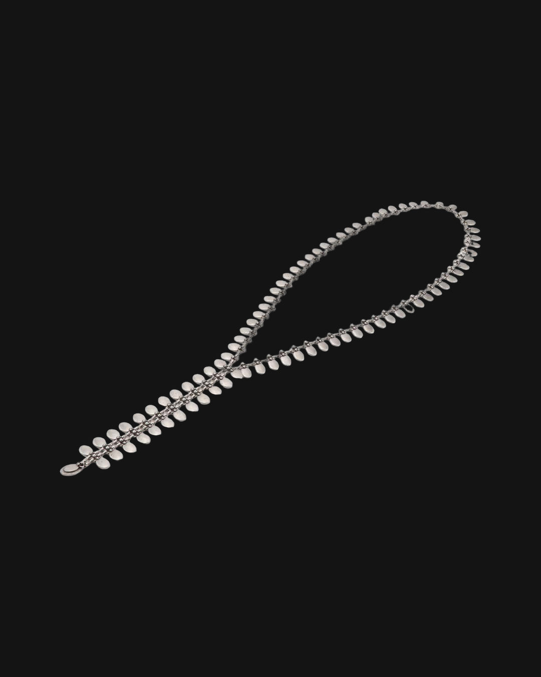 Pewter tab Y-necklace laid in a loose loop showing the row of small oval tabs, shown on a black background