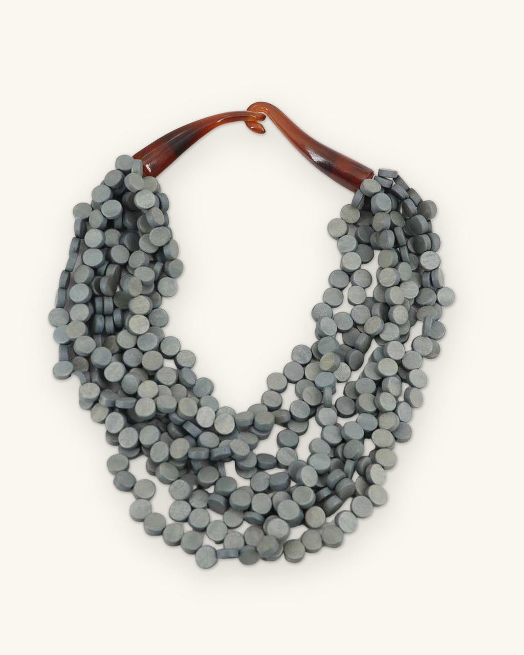 Slate gray dyed wood disc bib necklace with amber horn closure, handmade in the Philippines, shown on a sand background