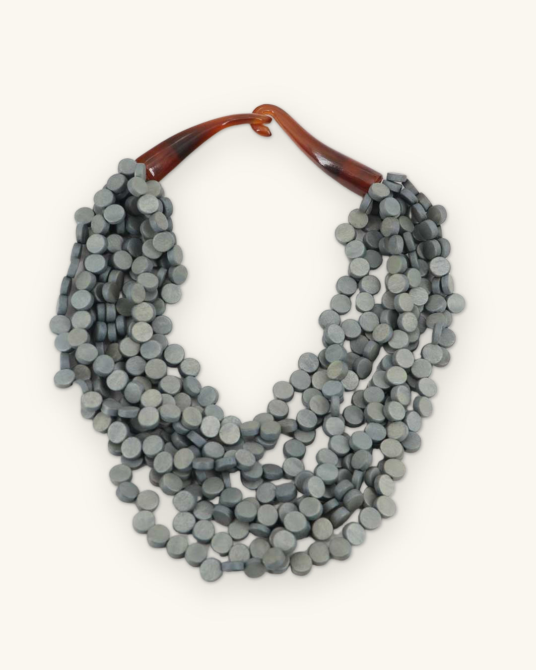 Slate gray dyed wood disc bib necklace with amber horn closure, handmade in the Philippines, shown on a sand background