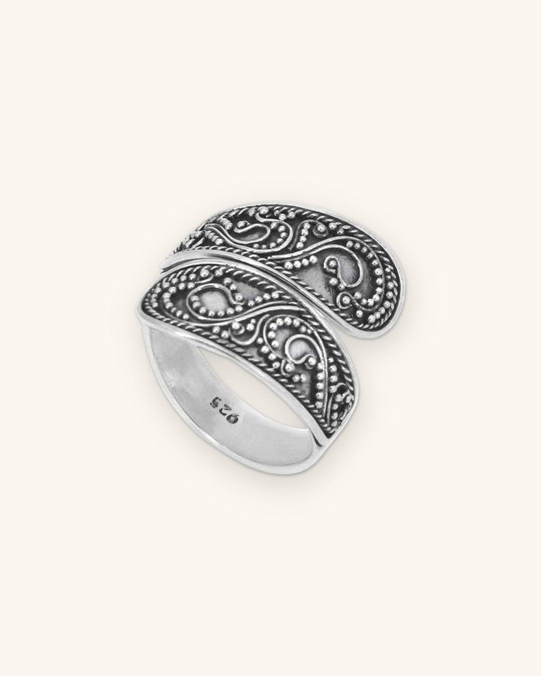 Sterling silver wraparound filigree ring with bead granulation and oxidized scrollwork, made in Bali, Indonesia, shown on a sand background