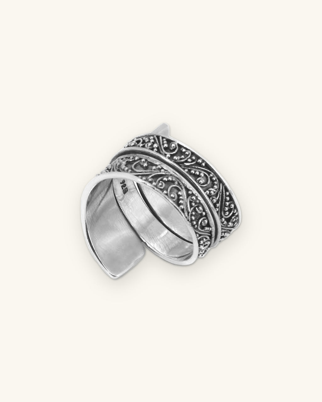 Sterling silver wide band filigree ring with scroll and granulation work, handmade in Bali, Indonesia, shown on a sand background
