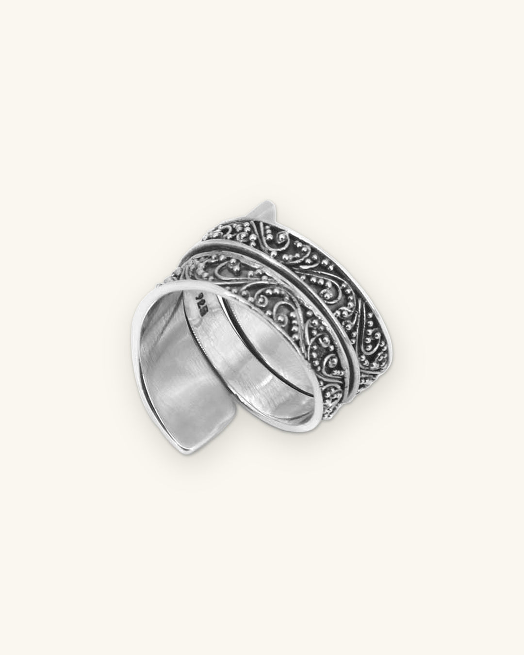 Sterling silver wide band filigree ring with scroll and granulation work, handmade in Bali, Indonesia, shown on a sand background