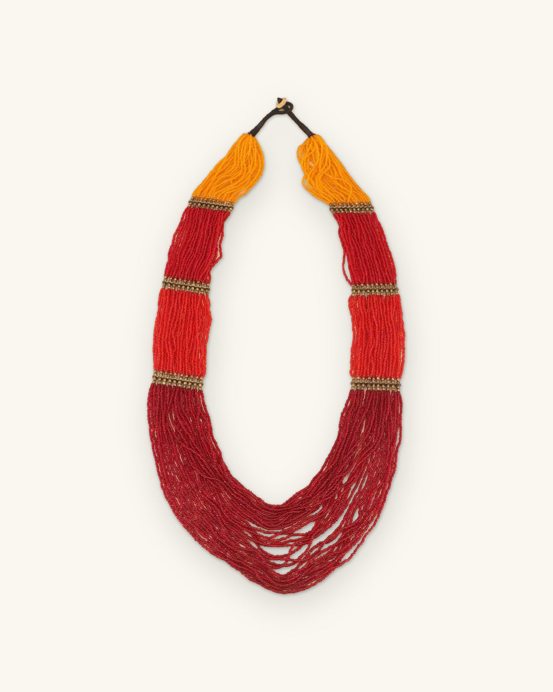 Sunrise gradient multi-strand beaded necklace with brass-tone spacer bars, full front view, shown on a sand background