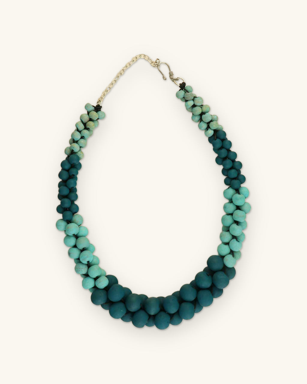 Twisted teal-to-turquoise gradient wood bead necklace with chain extender and hook clasp, shown on a sand background