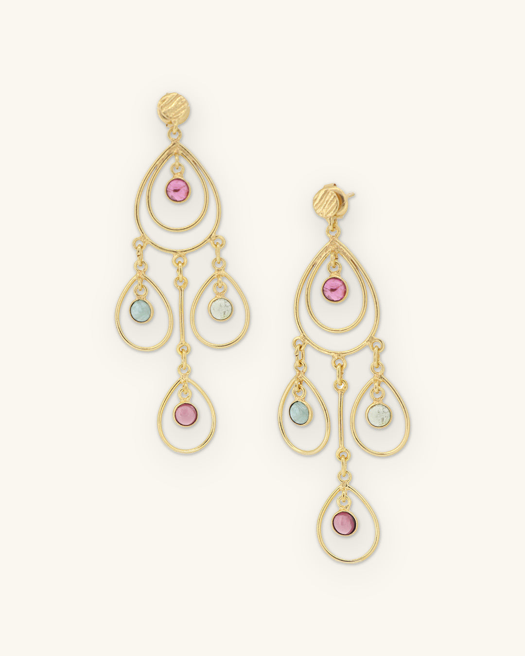 Gold-plated brass nested teardrop chandelier earrings with pink and green tourmaline, handcrafted in India, shown on a sand background