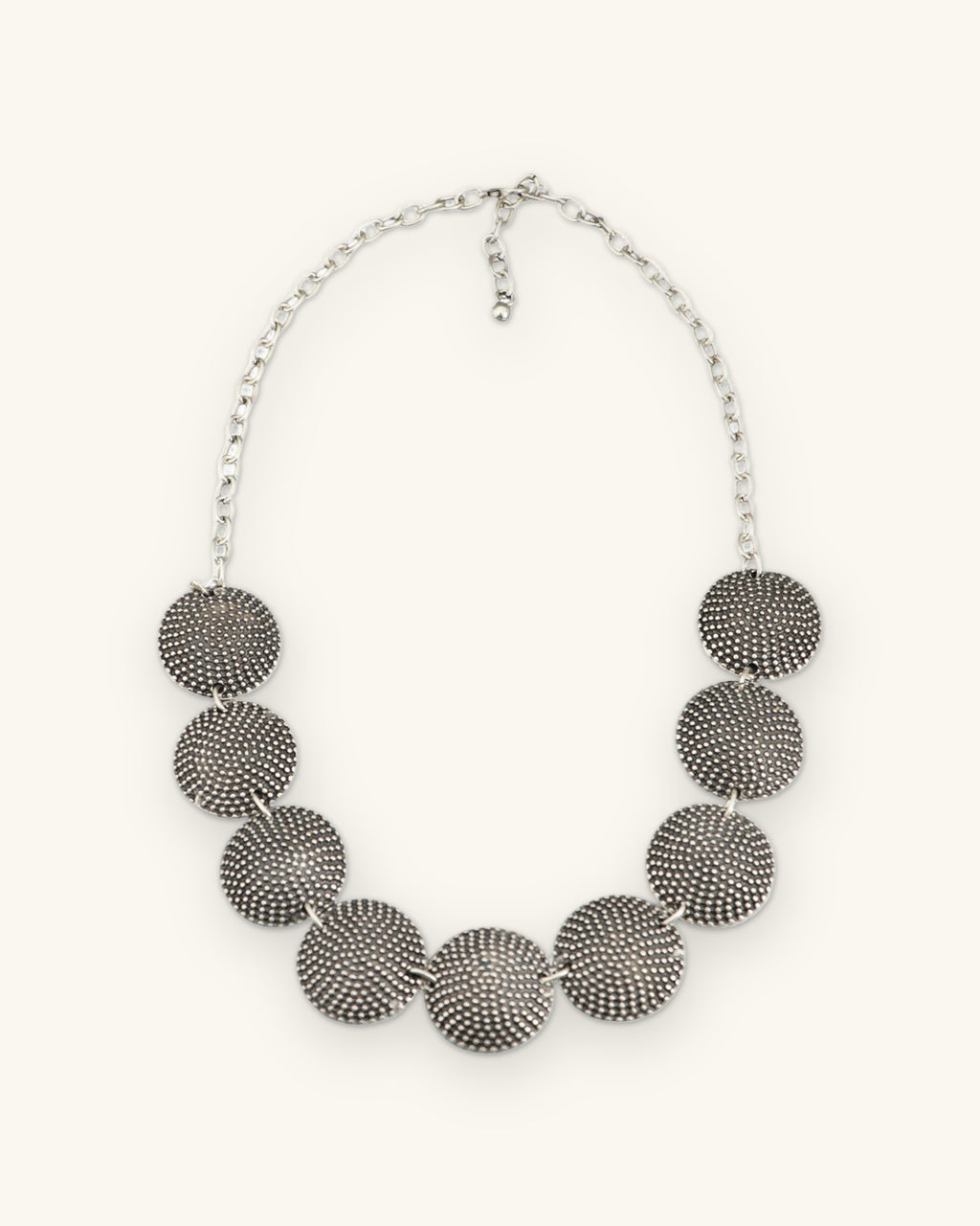 Graduated dome disc necklace with lobster clasp and extender chain, full front view, shown on a sand background