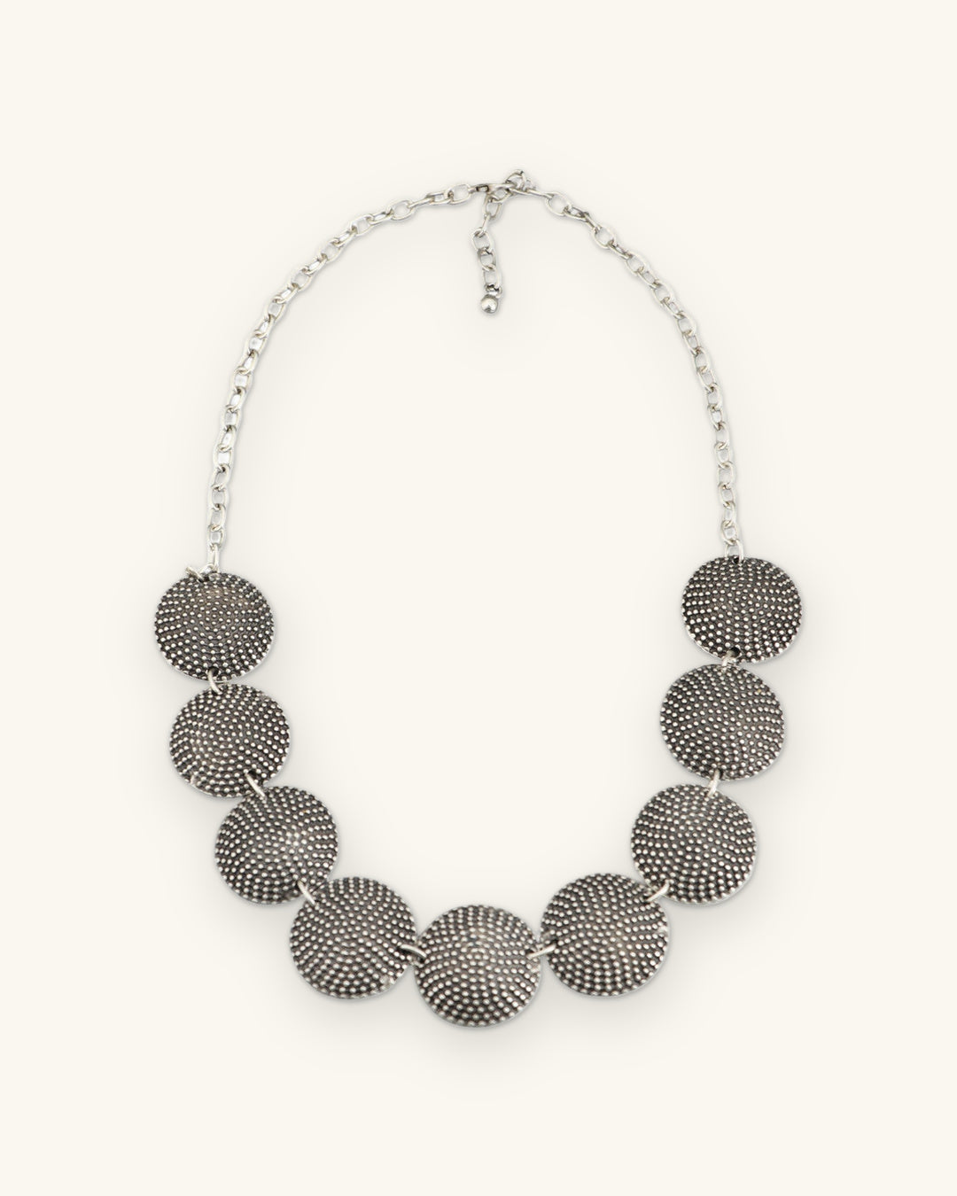 Graduated dome disc necklace with lobster clasp and extender chain, full front view, shown on a sand background