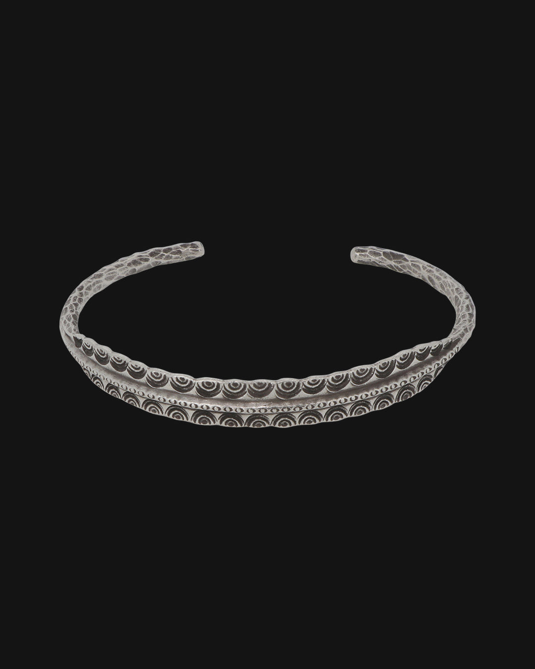 Front view of the open silver cuff with nested arc stamping along the center, shown on a black background