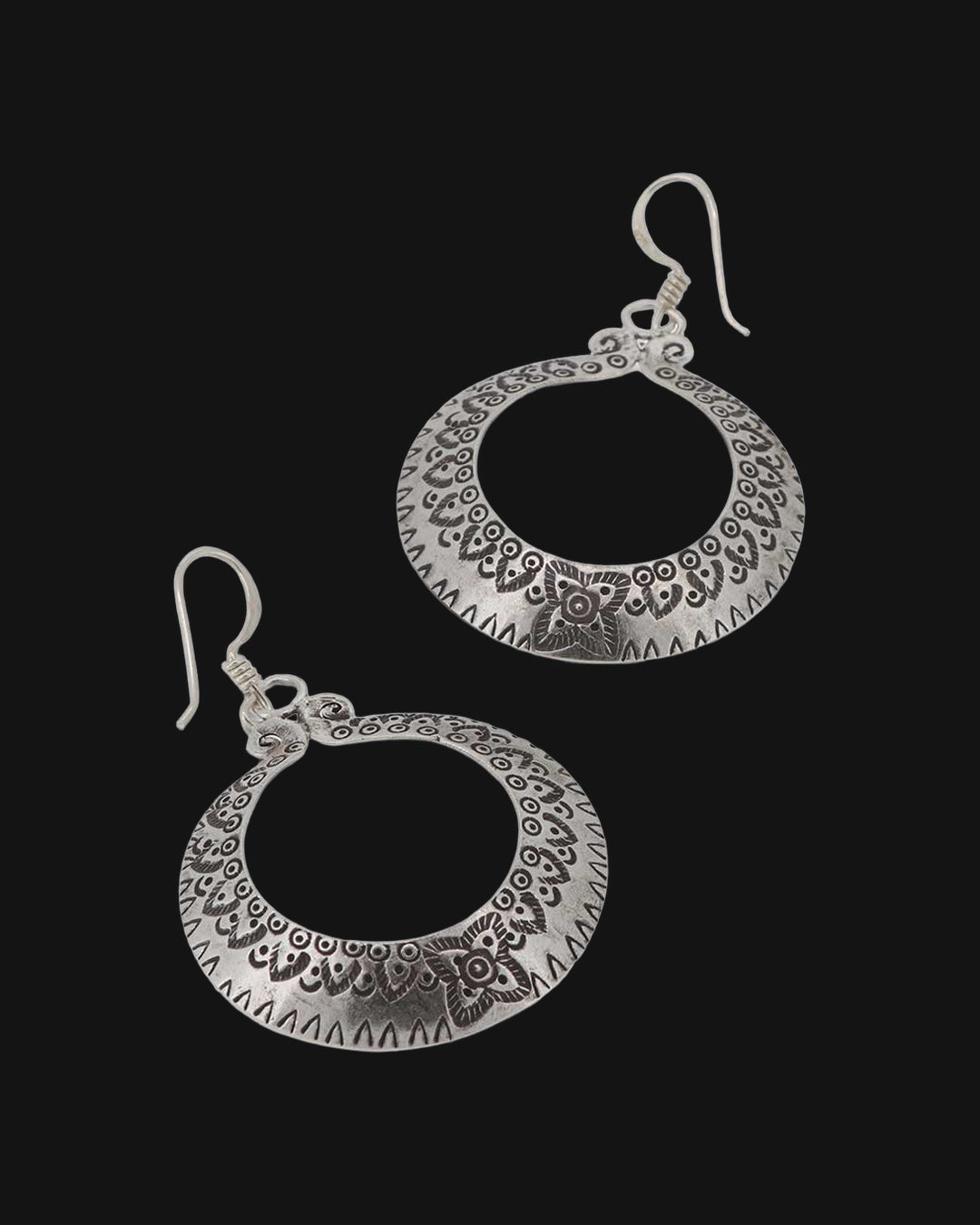 Pair of Thai Hilltribe silver crescent hoops with stamped floral border on French hook ear wires, shown on a black background
