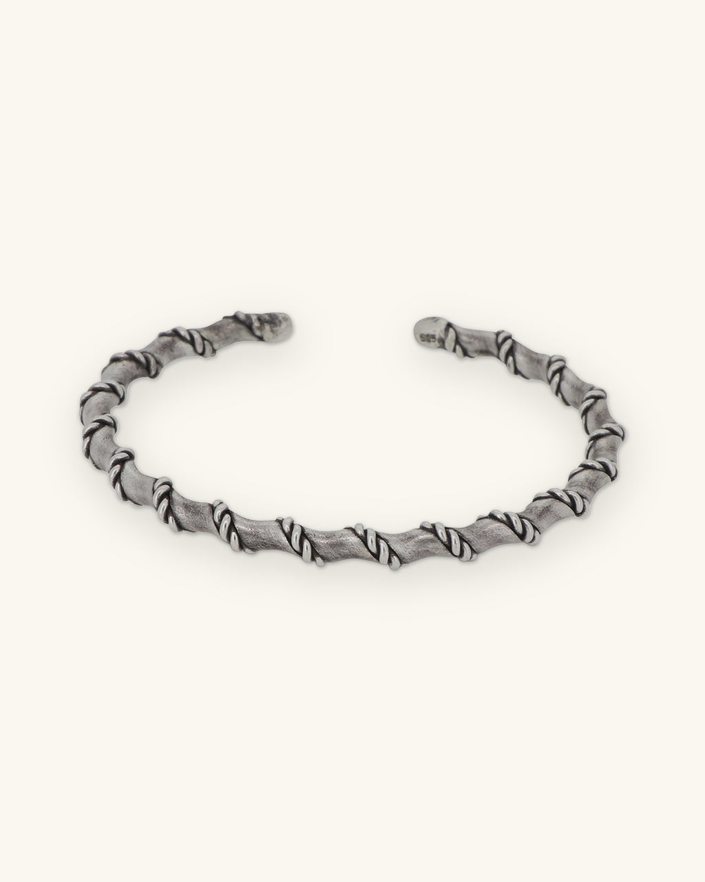 Oxidized sterling silver open cuff wrapped in a rope spiral, front view, shown on a sand background
