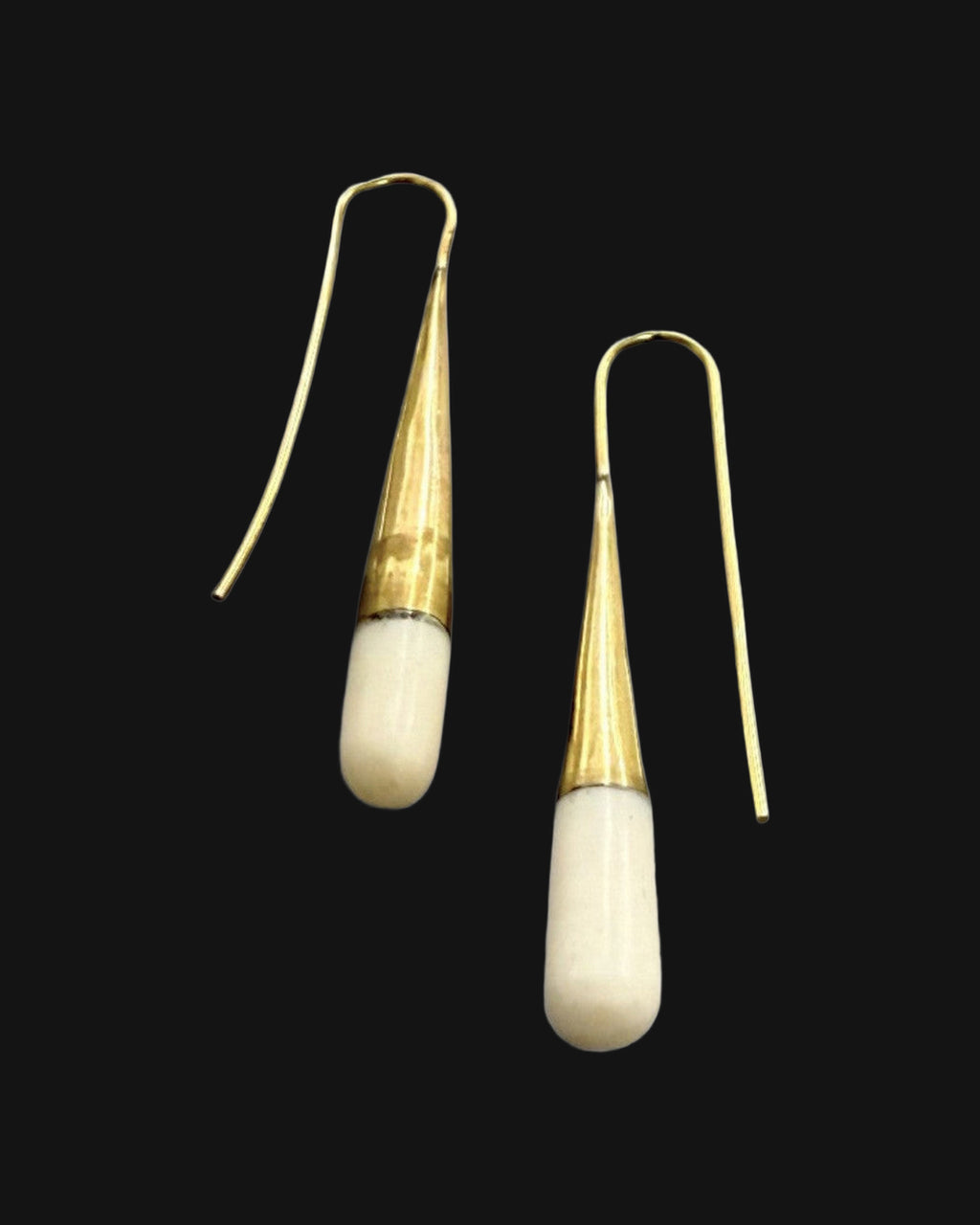 Brass and bone threader earrings at an angle showing the tapered cone and rounded bone drop, shown on a black background