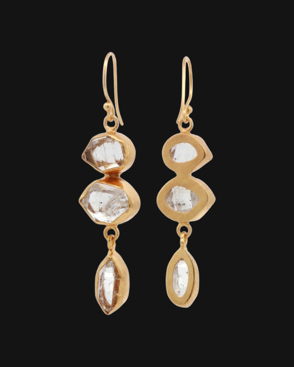 Herkimer quartz drop earrings, one turned to show the open-backed gold bezels, shown on a black background