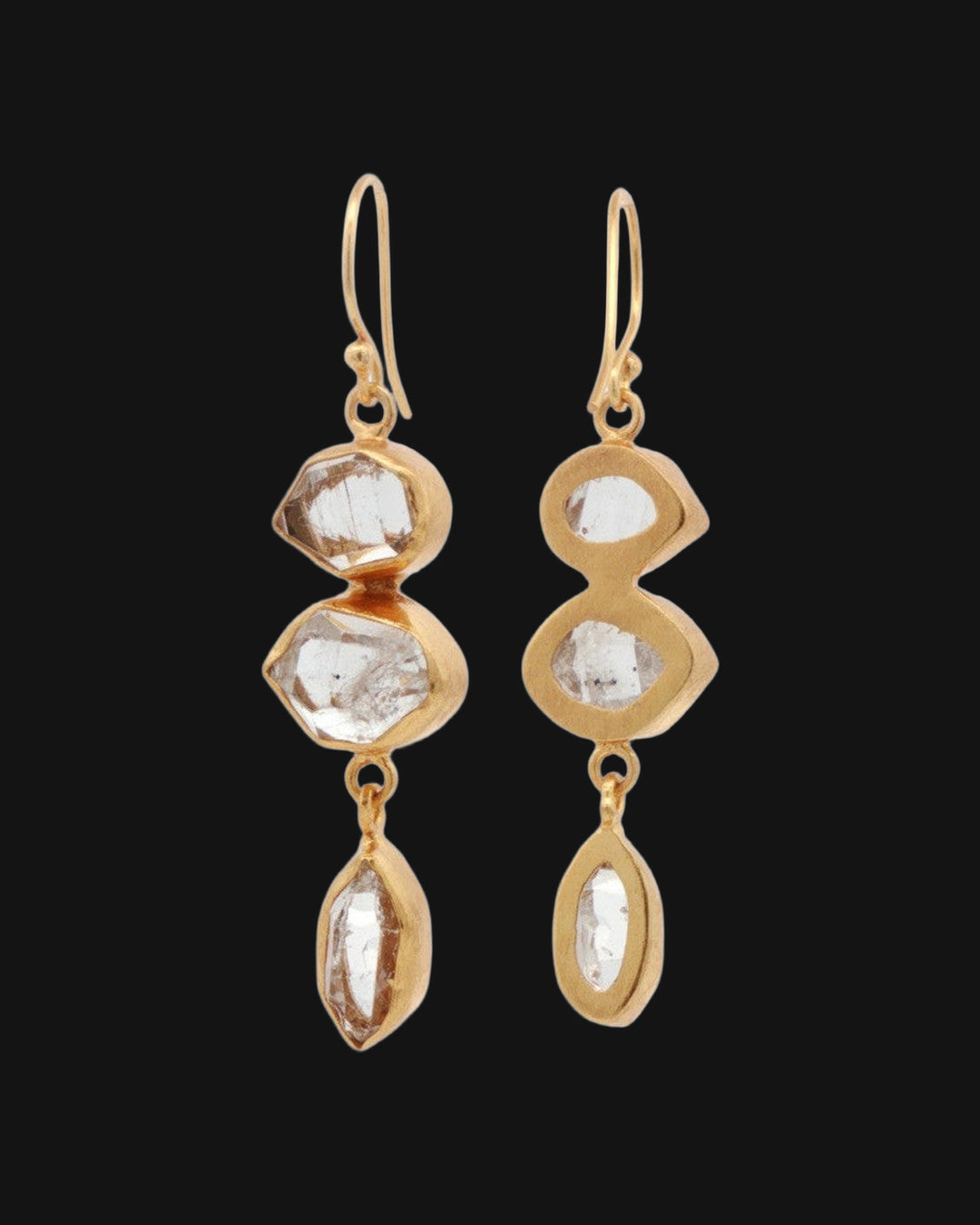 Herkimer quartz drop earrings, one turned to show the open-backed gold bezels, shown on a black background