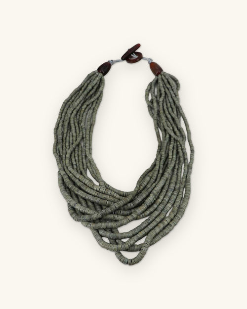 Multi-strand coconut disc necklace in Sage Gray with brown toggle clasp, shown on a sand background