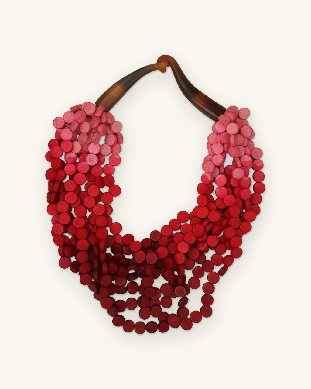 Multi-strand wooden disc necklace shading from pink to wine with a natural horn closure, from the Philippines, shown on a sand background