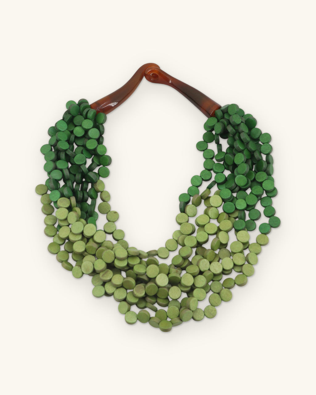 Twisted multi-strand wood disc necklace in dark and light green with horn closure, from the Philippines, shown on a sand background