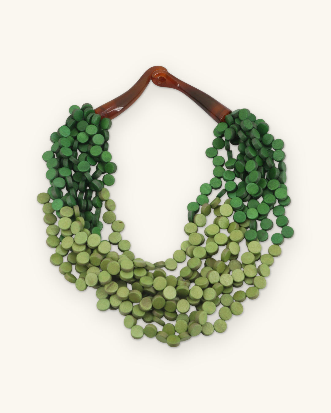 Twisted multi-strand wood disc necklace in dark and light green with horn closure, from the Philippines, shown on a sand background