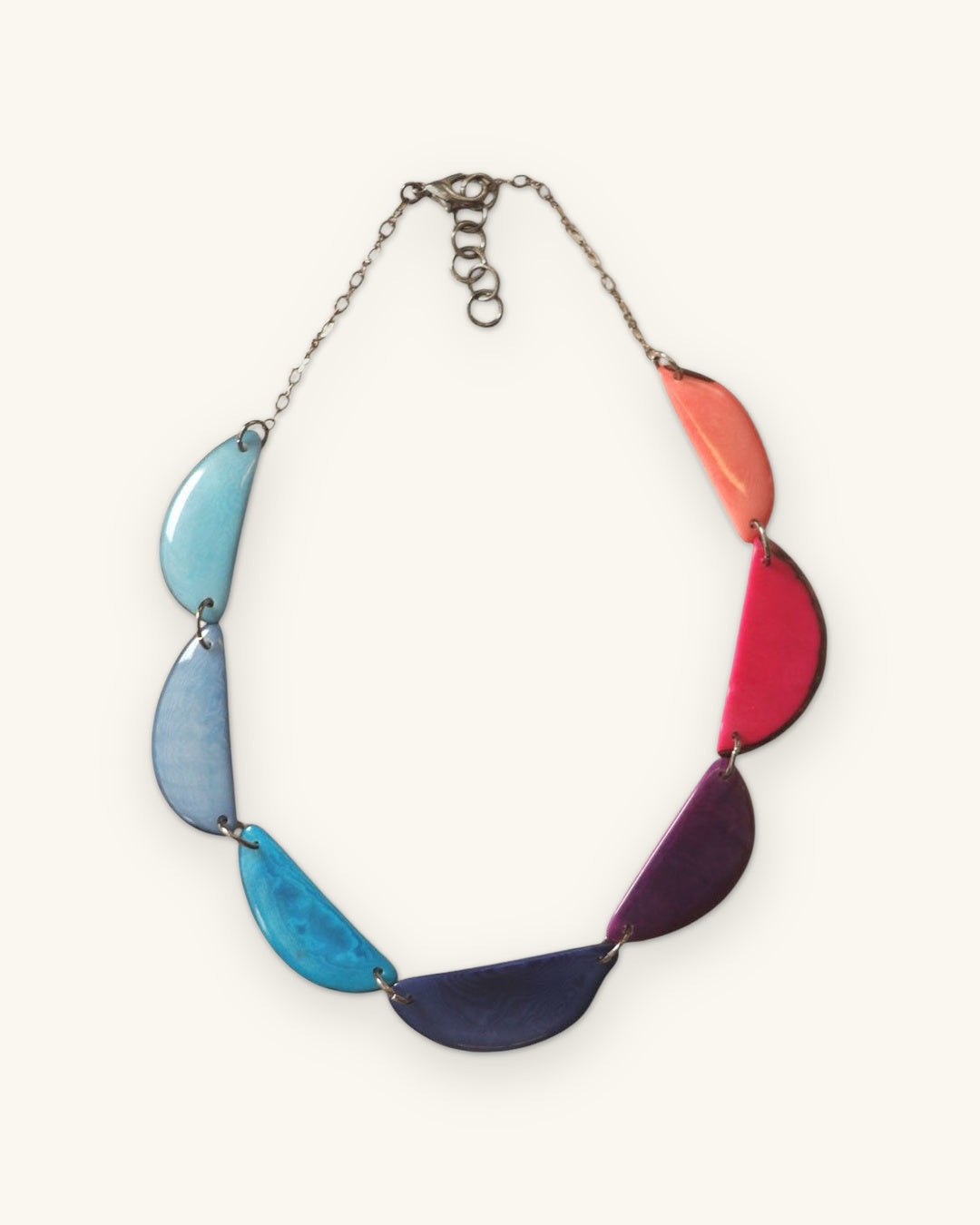Crescent tagua necklace on silver-tone chain with lobster clasp and extender, full view, shown on a sand background
