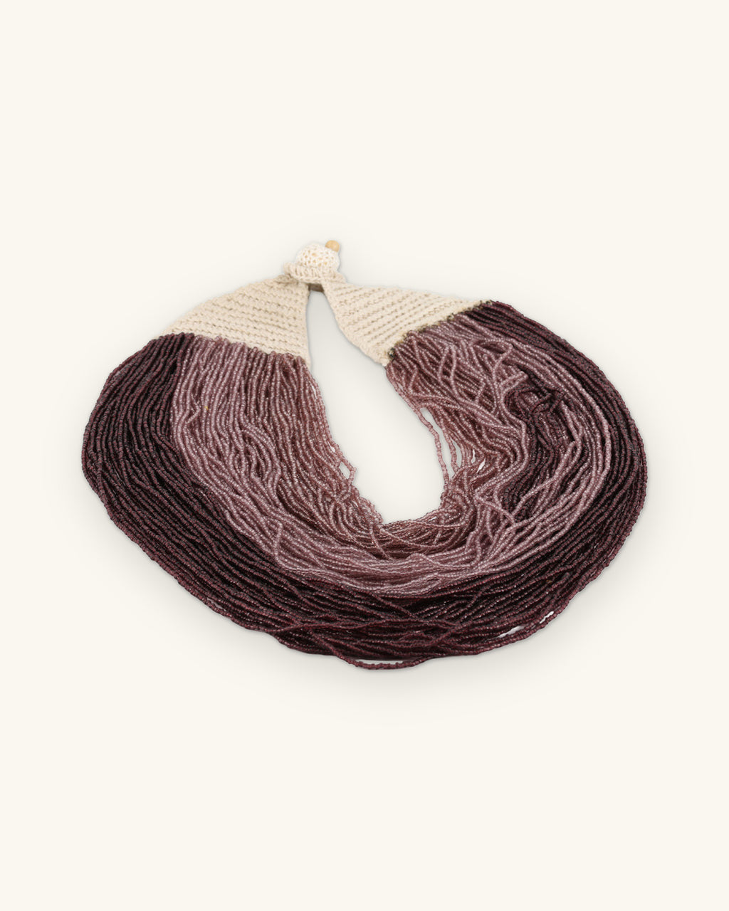 Purple ombré multi-strand necklace laid flat showing the cream crochet closure, shown on a sand background