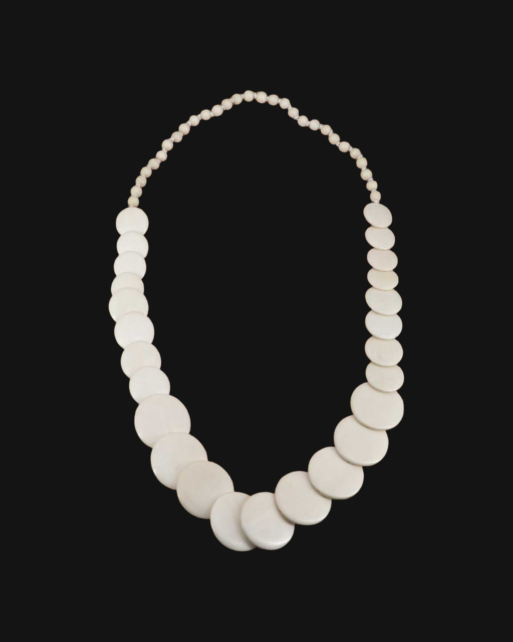 Cascading white wood disk necklace with graduated discs and small round beads, made in the Philippines, shown on a black background